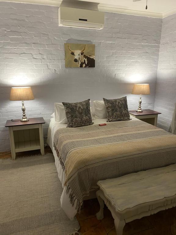 ein Schlafzimmer mit zwei Betten und zwei Tischen mit Lampen in der Unterkunft Die Kothuis in Malelane