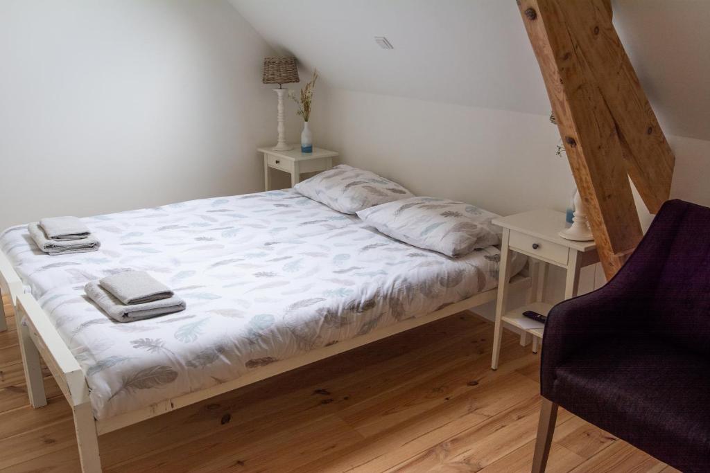 a bed in a room with a chair and a table at B&B De Kreek in Graauw