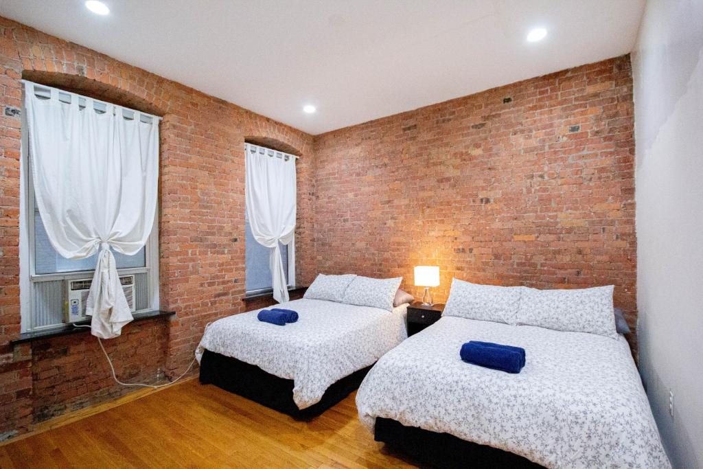 a bedroom with two beds and a brick wall at Studio Plus - One-Bedroom APT in New York