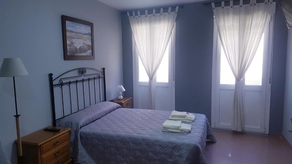 a blue bedroom with a bed and two windows at Apartamento Loft III Select Real Caldas de Reis in Caldas de Reis