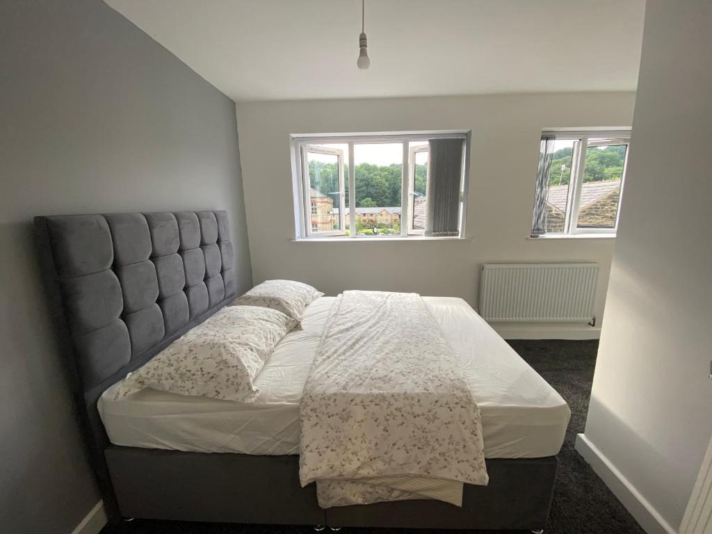 a bed in a bedroom with two windows at Entire Modern House in Greetland