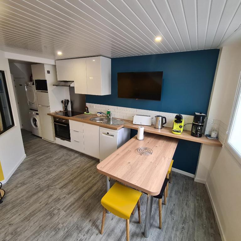 une cuisine avec une table en bois et une chaise jaune dans l'établissement T2 GUYNEMER RDC WIFI Plage à 80m Linge de lit fourni, à Les Sables-dʼOlonne