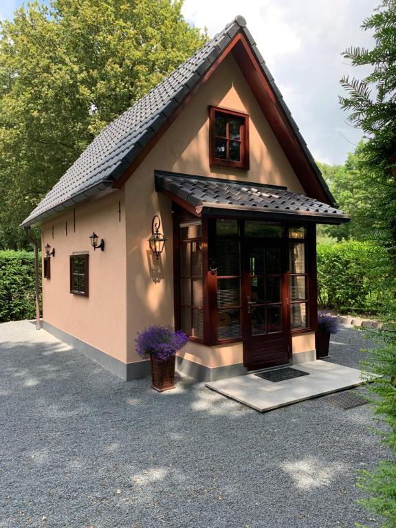 a small house with a large door on a driveway at Romantisch Gastenverblijf 'Het Vogelhuisje' in Lunteren