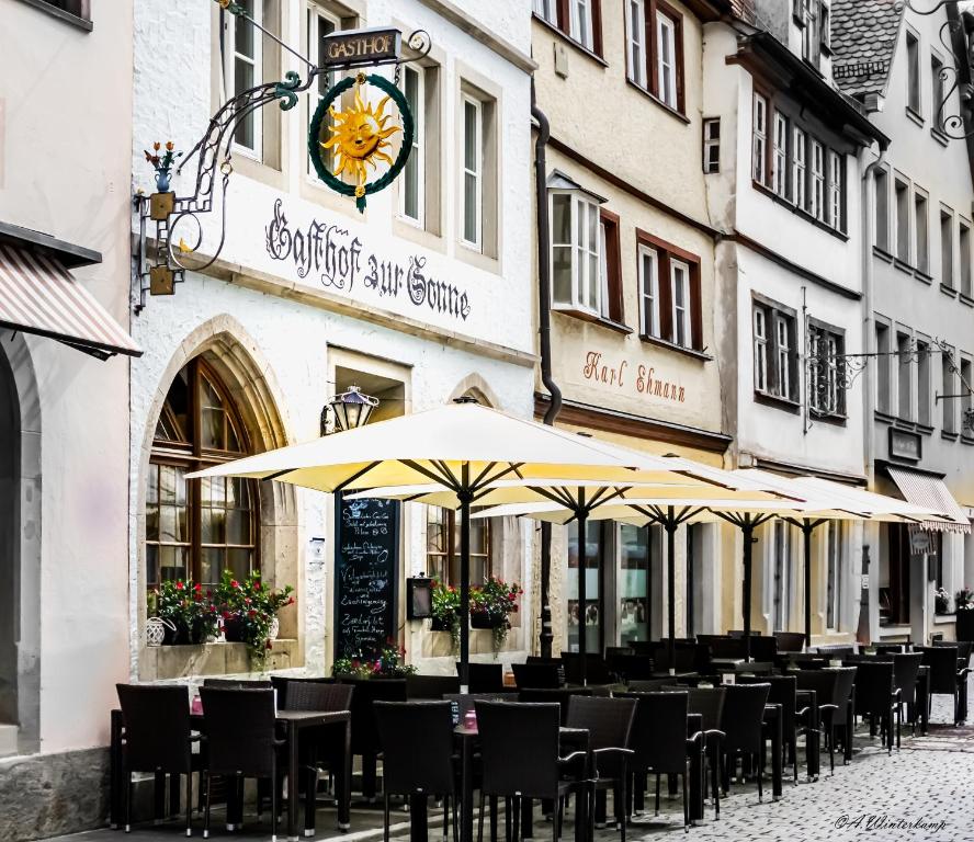 eine Reihe von Tischen mit Sonnenschirmen vor einem Gebäude in der Unterkunft Hotel Sonne - Das kleine Altstadt Hotel in Rothenburg ob der Tauber