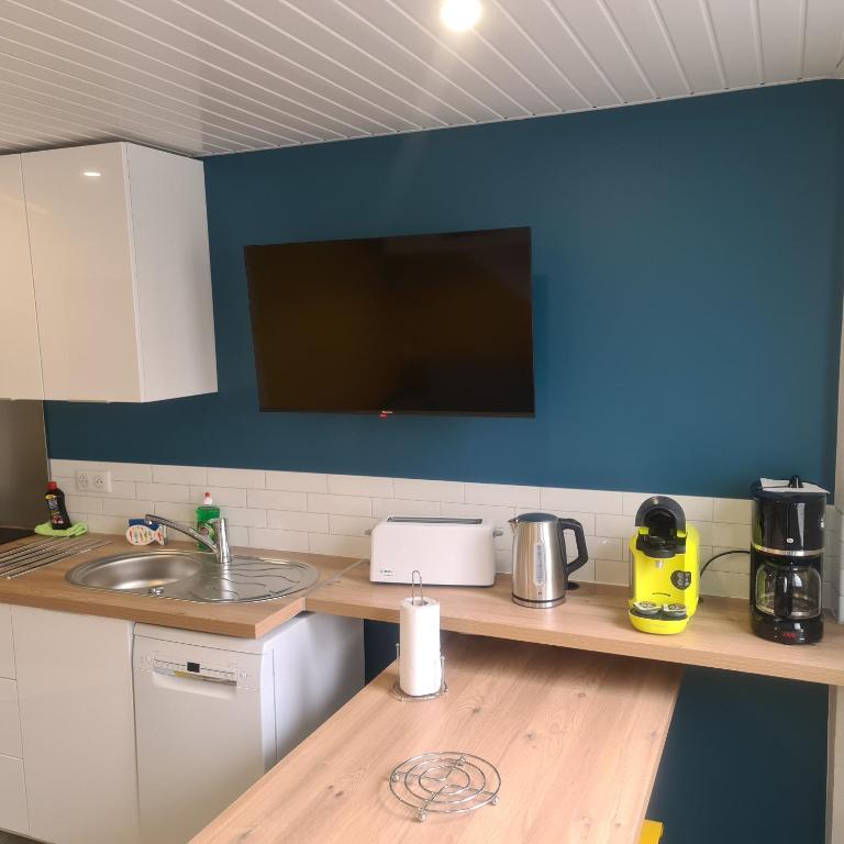 a kitchen with a sink and a tv on a blue wall at T2 GUYNEMER RDC WIFI Plage à 80m Linge de lit fourni in Les Sables-d&#39;Olonne