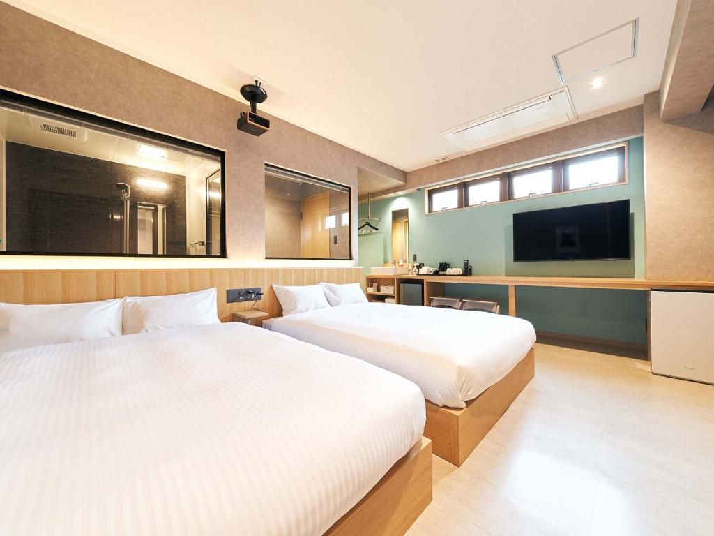 a hotel room with two beds and a tv at Rakuten STAY naha-tomarifuto 1F Twin Room in Naha