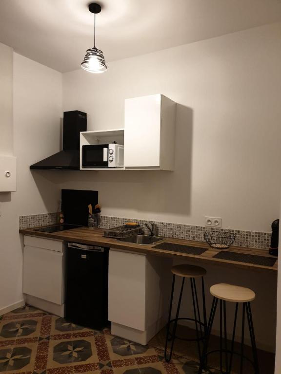 une cuisine avec un comptoir, un four micro-ondes et des tabourets dans l'établissement Studio Boffil centre historique Perpignan, à Perpignan
