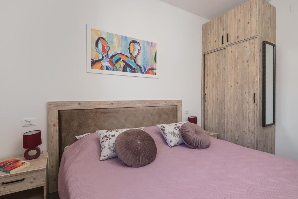 een slaapkamer met een roze bed met 2 kussens bij Sky Airport Apartments in Močići