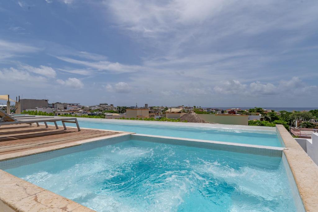 a large blue swimming pool with a wooden deck at Papaya 15 Apartments in Playa del Carmen