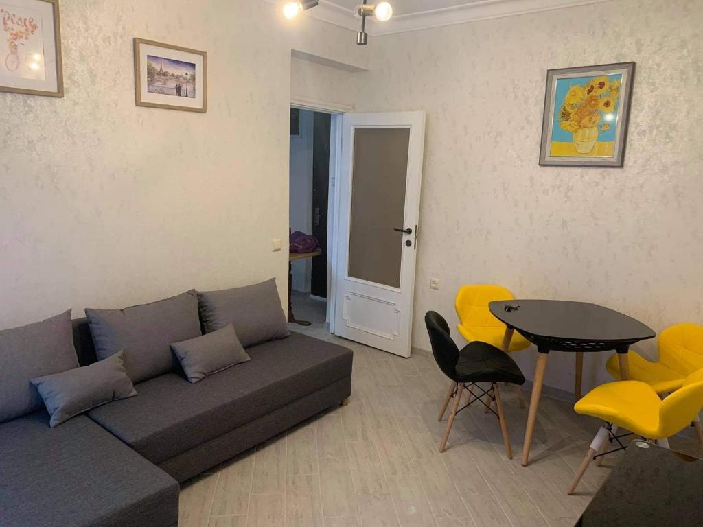 uma sala de estar com um sofá, uma mesa e cadeiras em Apartment Amest em Batumi