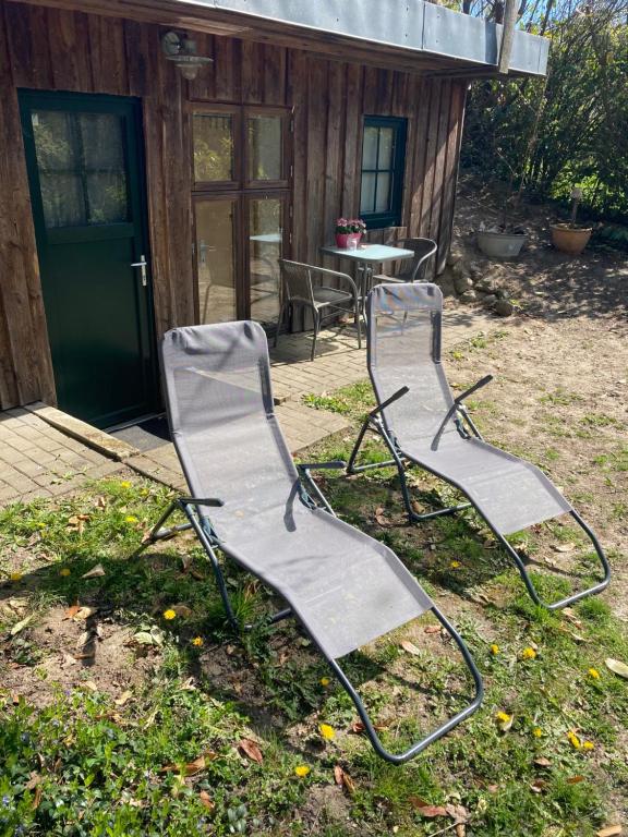 dos sillas sentadas en el césped frente a una cabaña en Kleines Ferienhäuschen im Grünen am Wasser, en Grönwohld