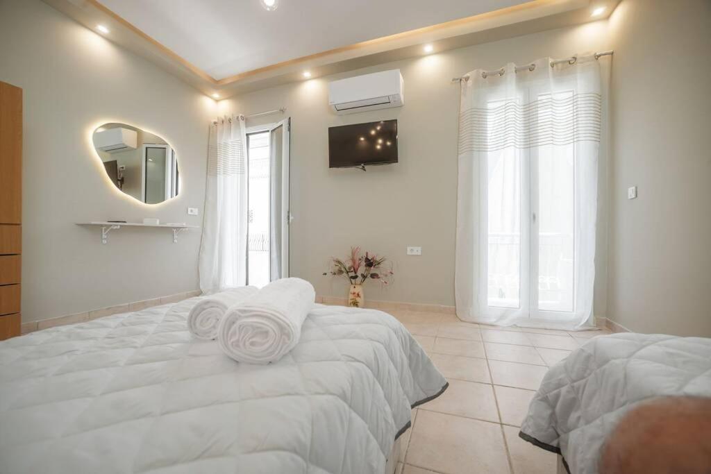 ein weißes Schlafzimmer mit einem großen Bett und einem Spiegel in der Unterkunft El Sueño de Zante 2nd City Center Apartments in Zakynthos