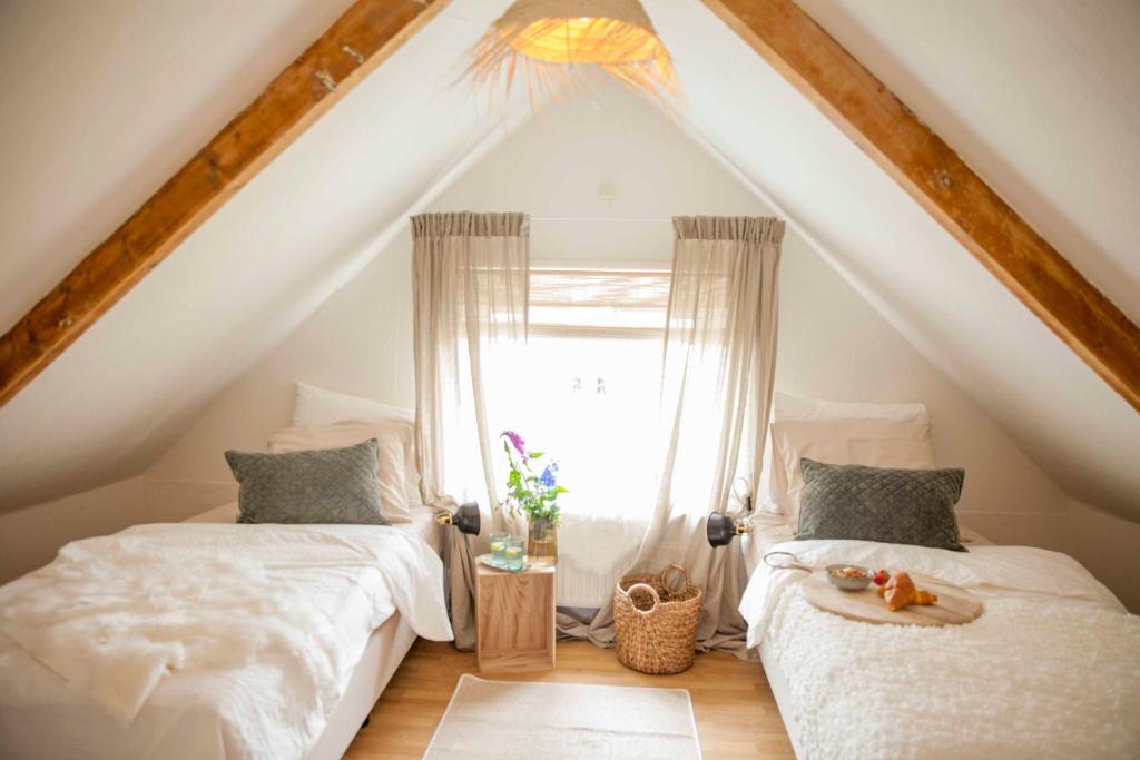 a attic bedroom with two beds and a window at Vakantiehuisje Ons Plekje 6 personen - Zeezand Recreatie in Stolpen