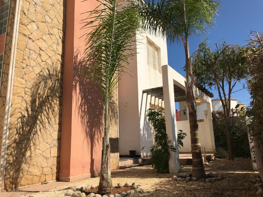 un edificio con palmeras delante en Villa à moins de 500m de la plage 3 Chambres et 4 SDB, en Saidia 
