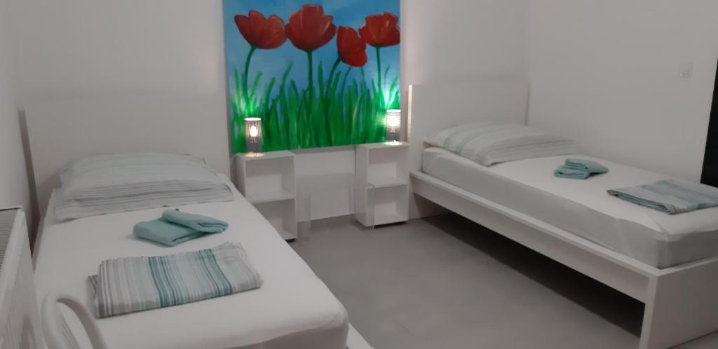 a room with two beds and a painting of red tulips at Hannas Paradise - Villa Evi in Skafidia