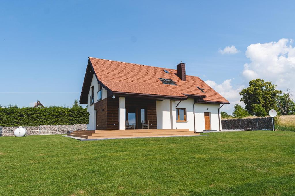 a small house with a red roof on a grass field at Dwa Wiatry in Trygort