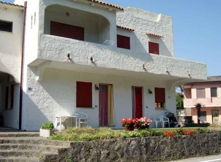 Biały dom z czerwonymi drzwiami i schodami w obiekcie Apartments in Rosolina Mare 25092 w mieście Rosolina Mare