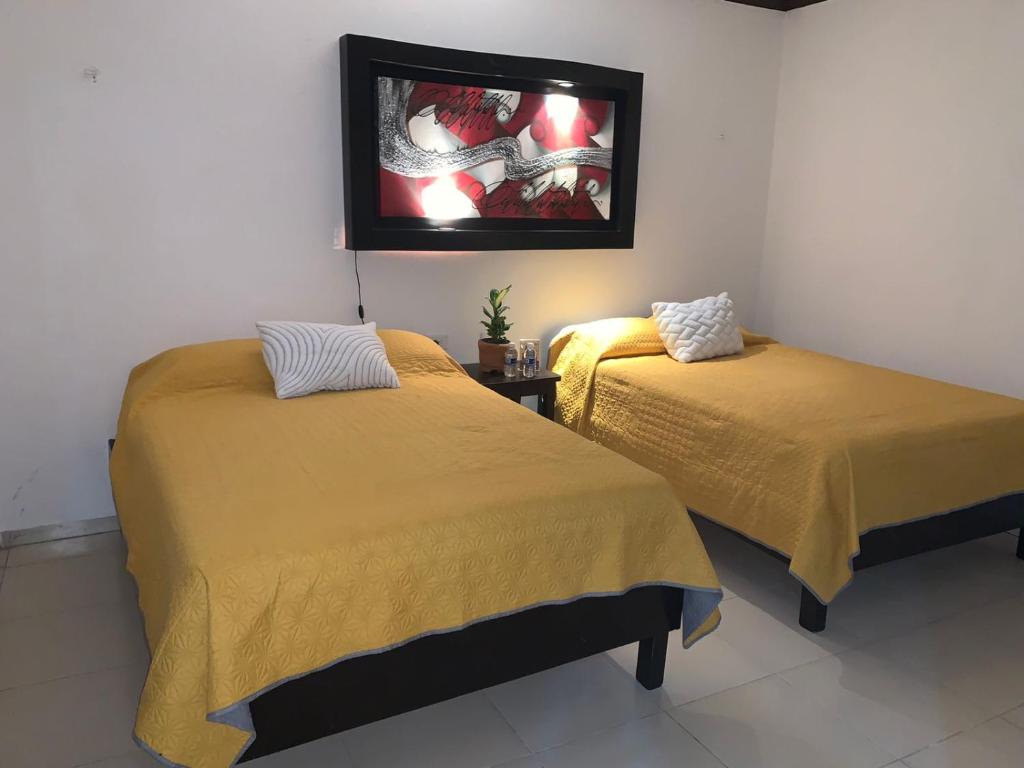 2 Betten in einem Zimmer mit einem TV an der Wand in der Unterkunft Casa Las Palmas in Tizimín