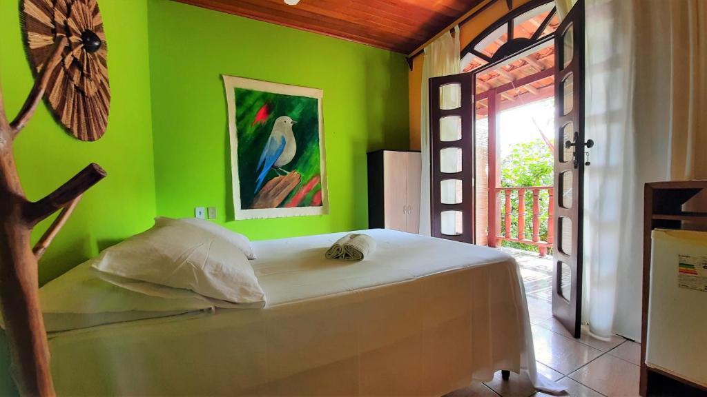 Un dormitorio con una pared verde y una cama. en Pousada Ilha De Boipeba, en Isla de Boipeba