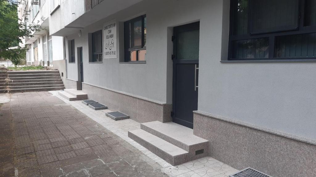 a building with a door and steps next to a sidewalk at Ая in Vratsa