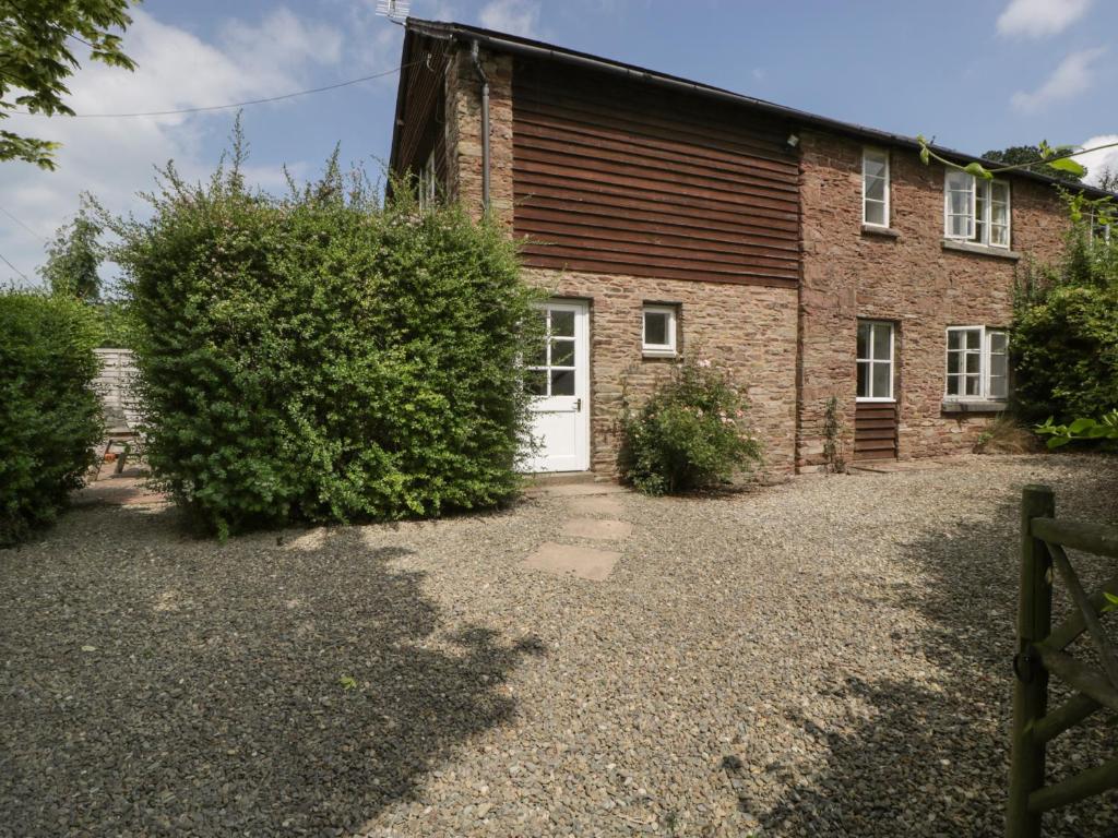 uma velha casa de tijolos com uma porta branca em Wheelbarrow Cottage em Stoke Prior