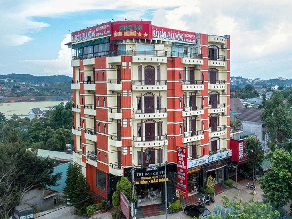 a red and white building with a river behind it at Sai Gon Dak Nong Hotel in Gia Nghĩa