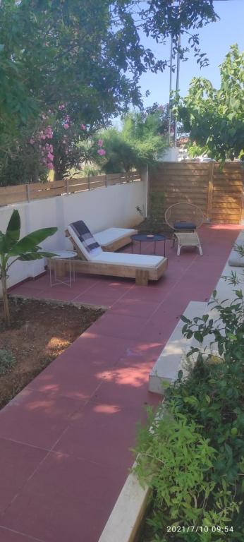 un patio avec deux bancs et une table dans l'établissement Seaside Jacaranda, à Schinias