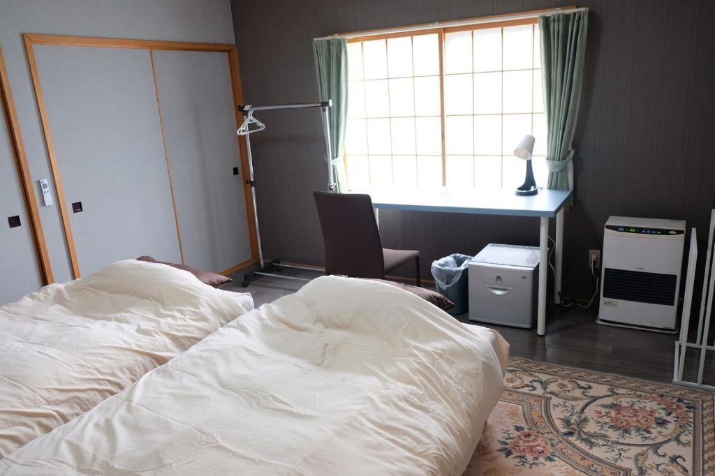 1 dormitorio con cama, escritorio y ventana en 富貴の里レジデンス en Ombetsu