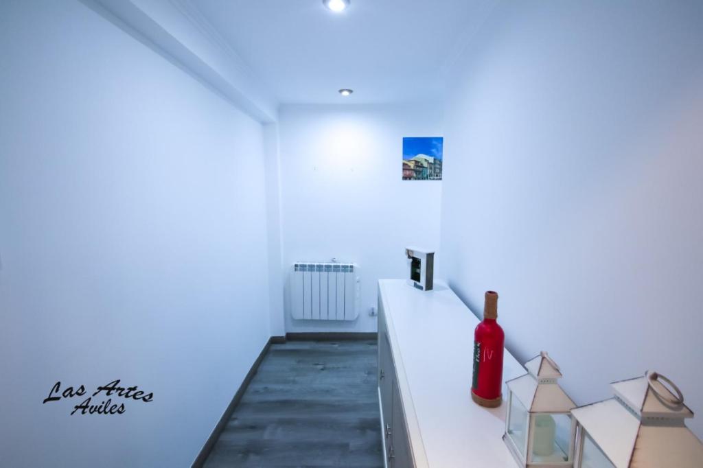 Habitación blanca con una botella de vino en la barra en Piso las Artes en Avilés