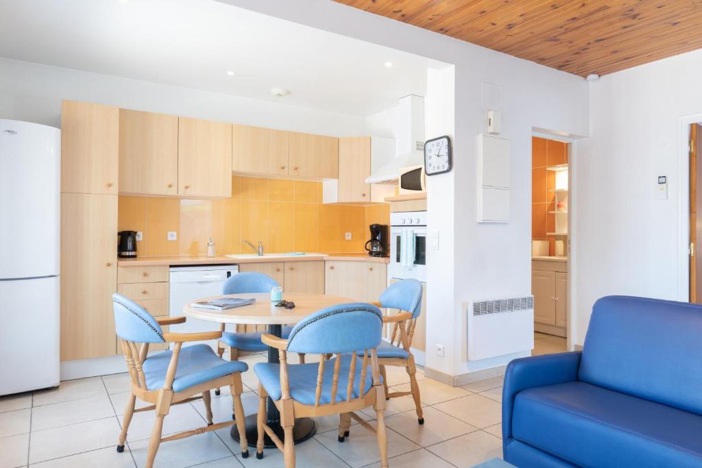 a kitchen with a table and chairs and a blue couch at Résidence Amaréna in Saint-Paul-lès-Dax