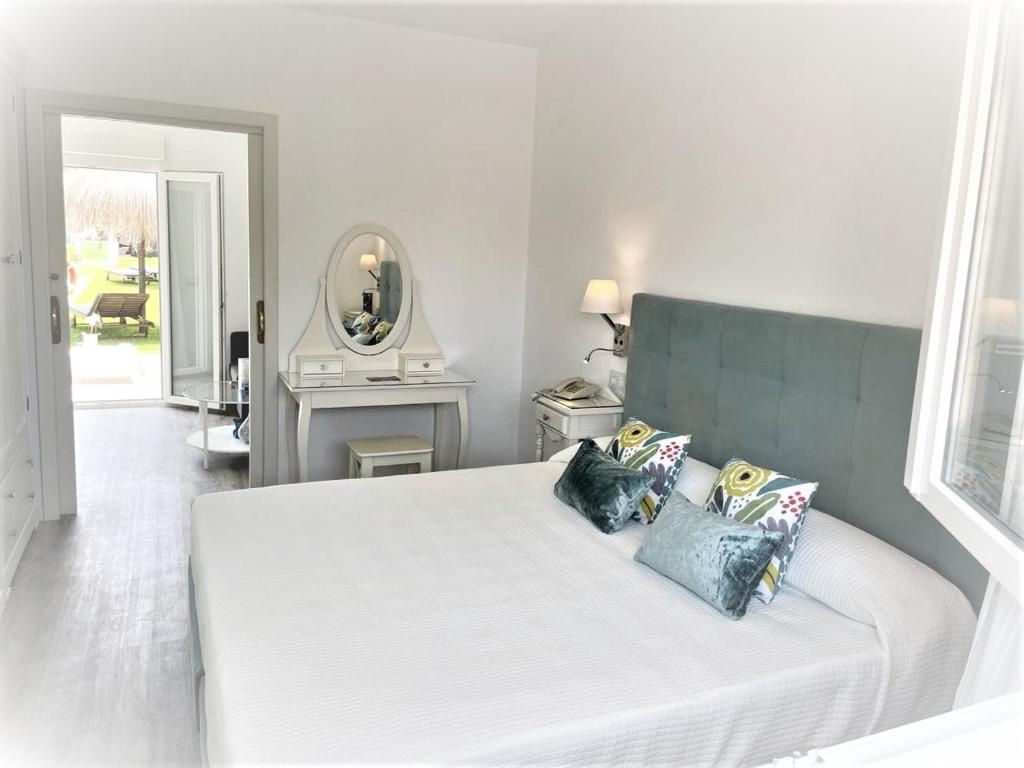 um quarto com uma cama branca com almofadas e um espelho em Hotel Malaga Picasso em Málaga