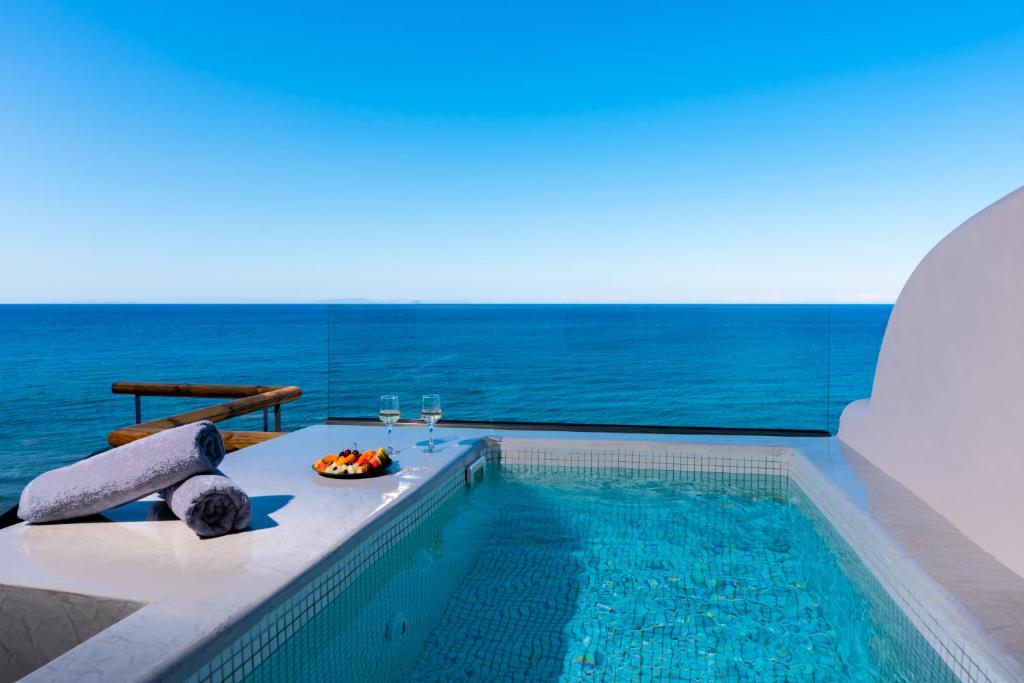 una piscina con mesa y copas de vino en Neoma Luxury Suites en Karterados