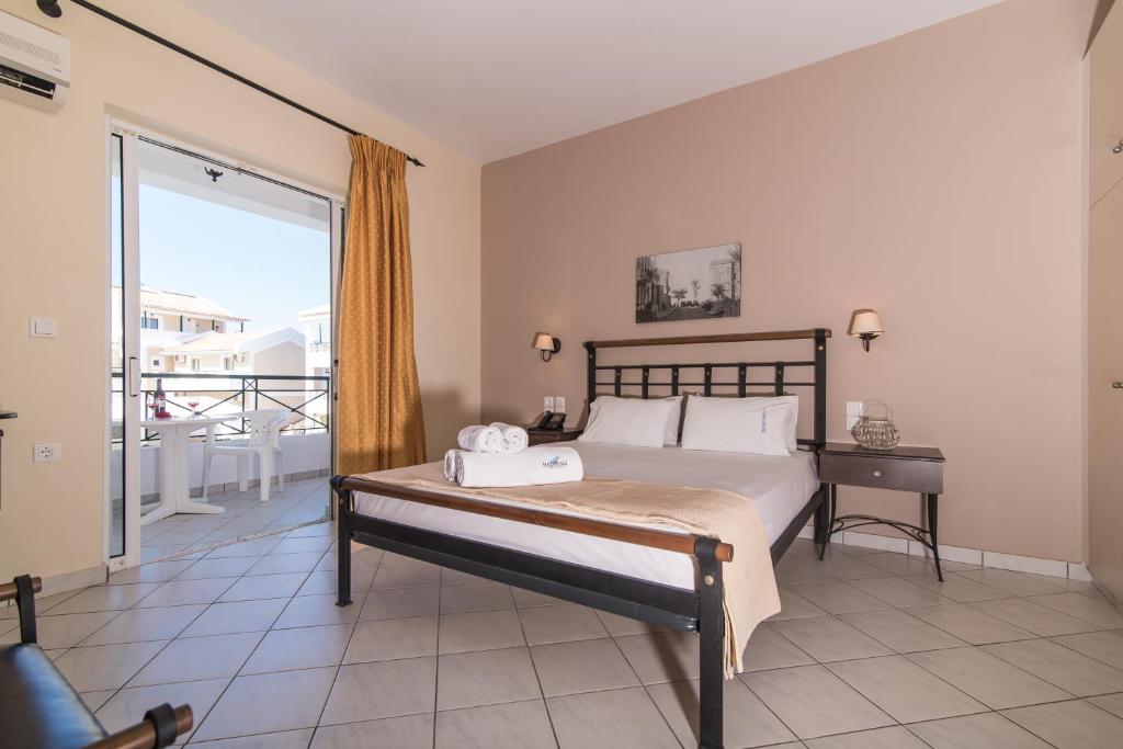 a bedroom with a large bed and a large window at Maistrali Hotel Zante in Tragaki