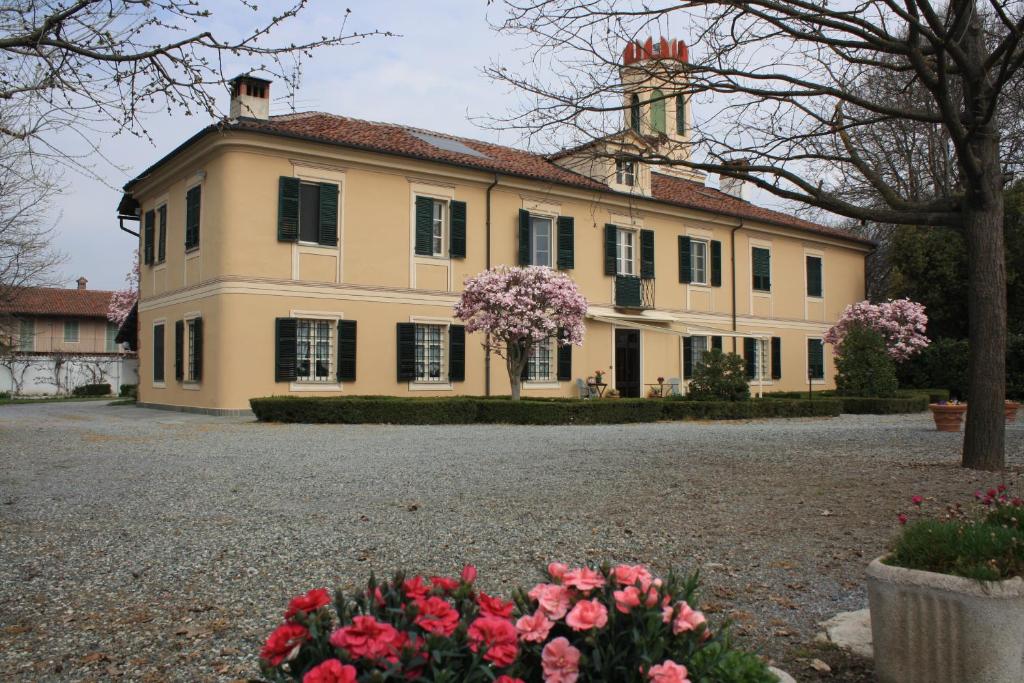 una casa grande con flores rosas delante en B&B Villa Cardellini en Savigliano