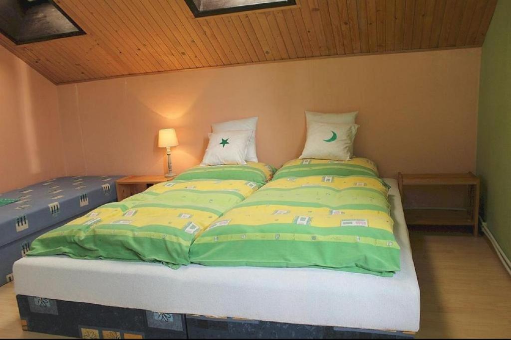a bed with green and yellow sheets in a room at Penzion Victoria in Habovka