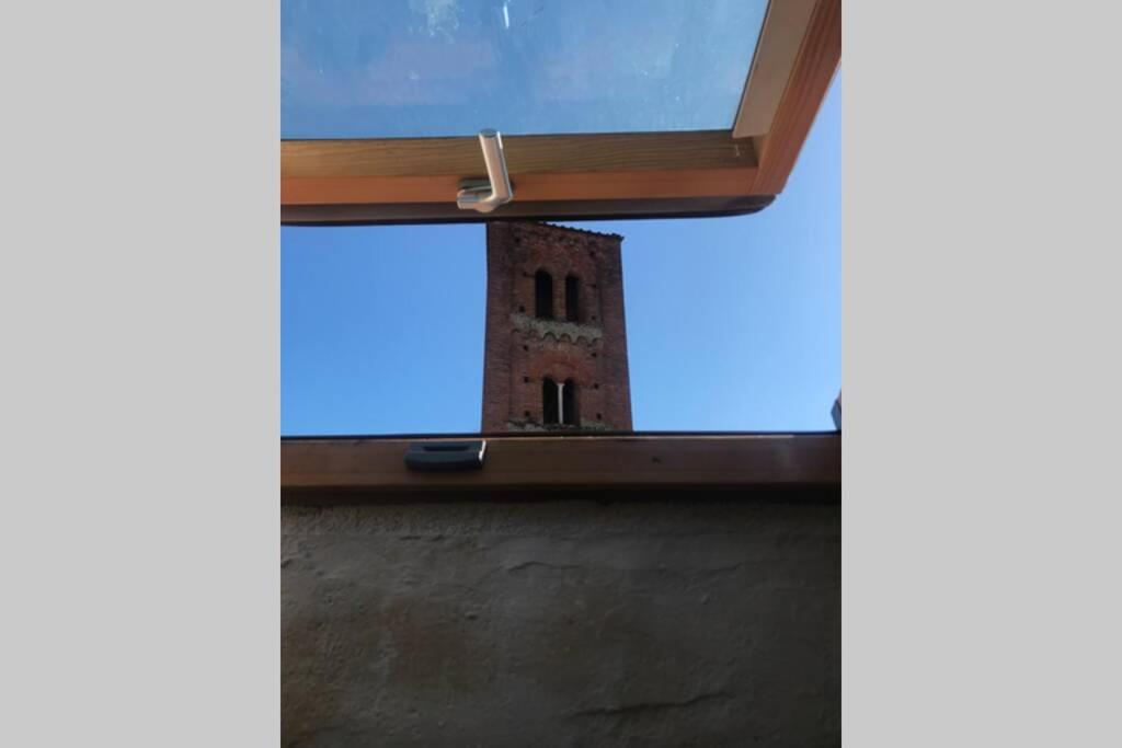 ein Fenster mit einem Backsteinturm im Hintergrund in der Unterkunft mansarda centro storico in Lucca