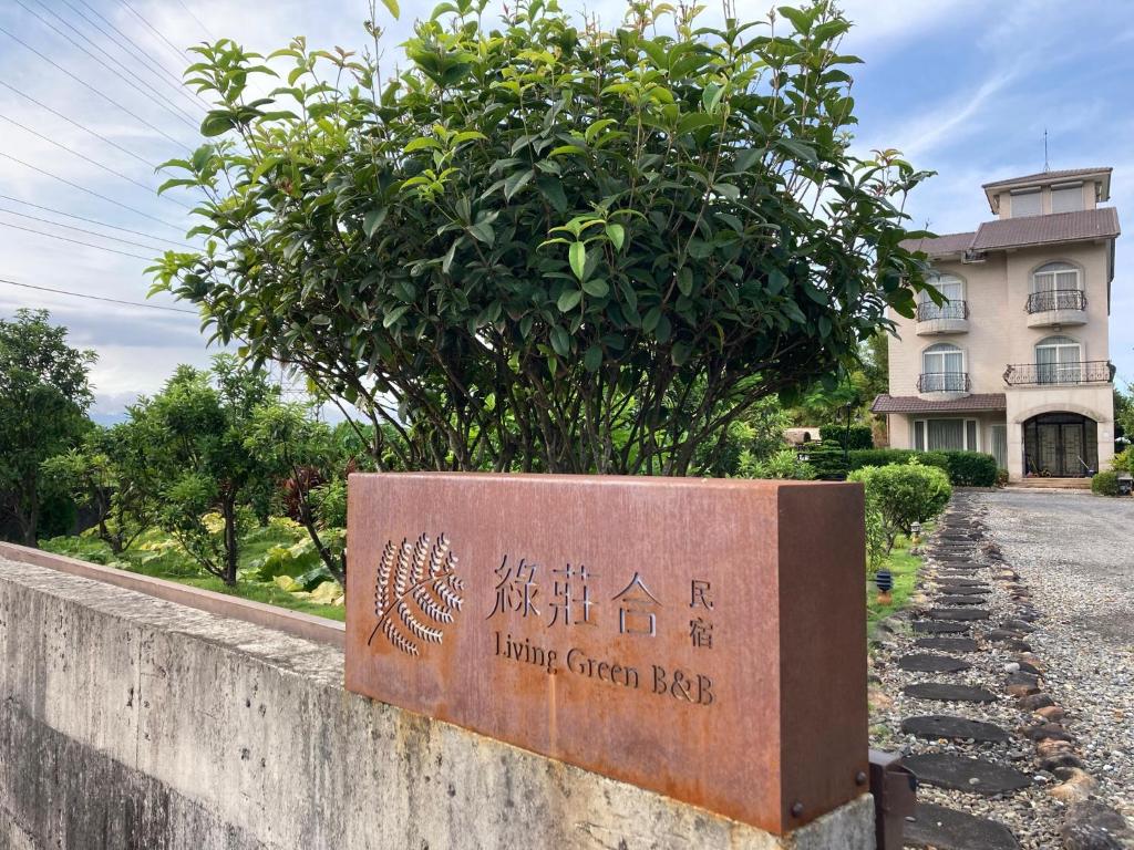 a sign in front of a building with a tree at LivingGreen B&amp;B in Luodong
