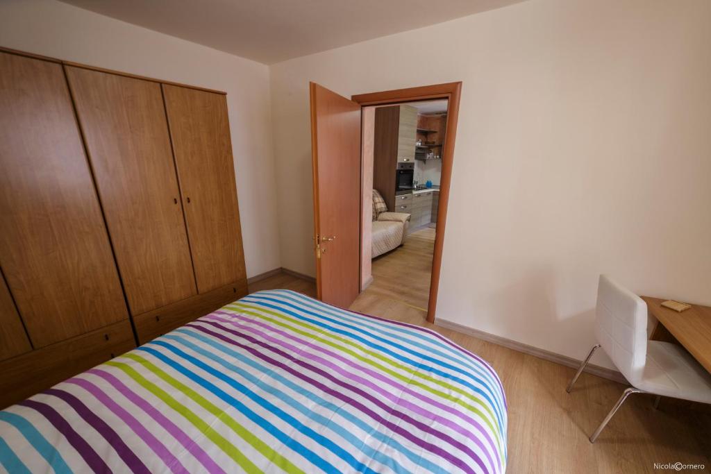 Un dormitorio con una colorida cama de rayas y un espejo en Dimora Gilles, Aosta, Alloggio ad uso turistico VDA ISSOGNE n0003, en Issogne