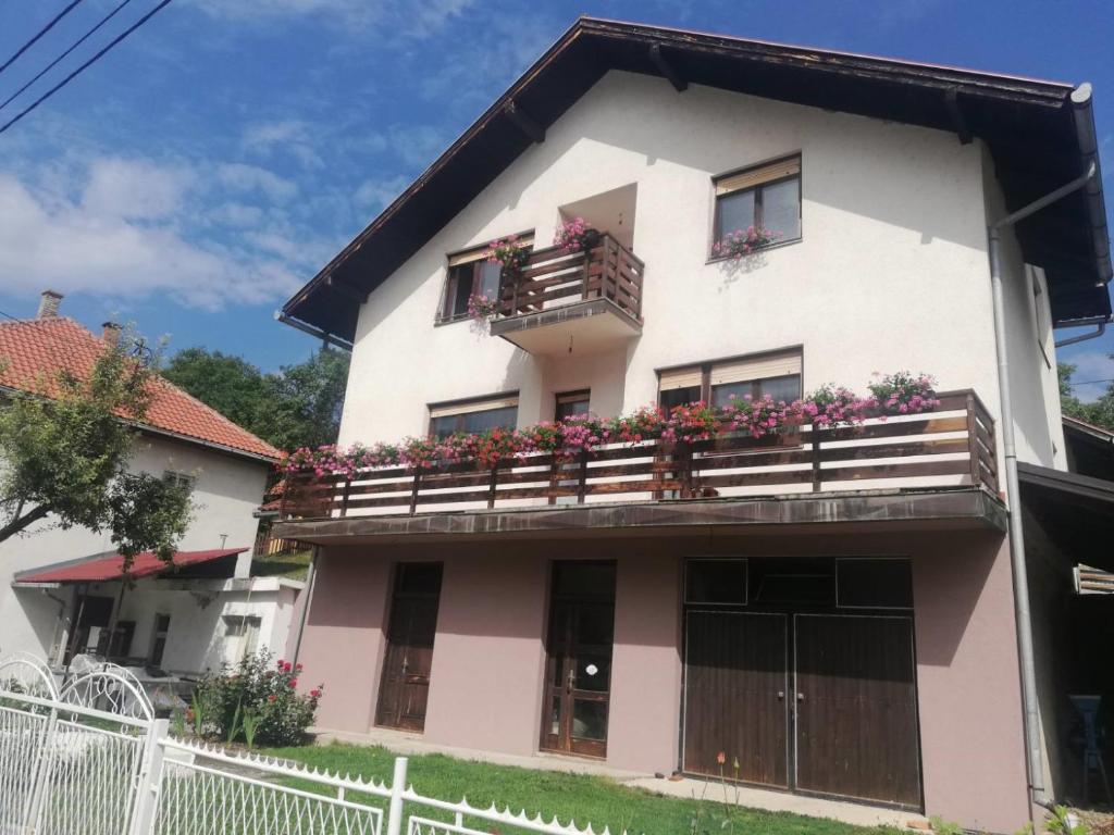 Casa blanca y rosa con flores en los balcones en Apartman Draga, en Mokra Gora
