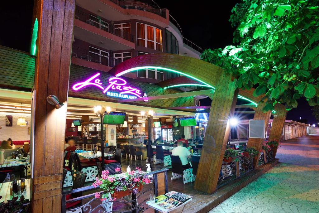 a restaurant with a neon sign on the side of a building at La Piazza Family Hotel in Sunny Beach