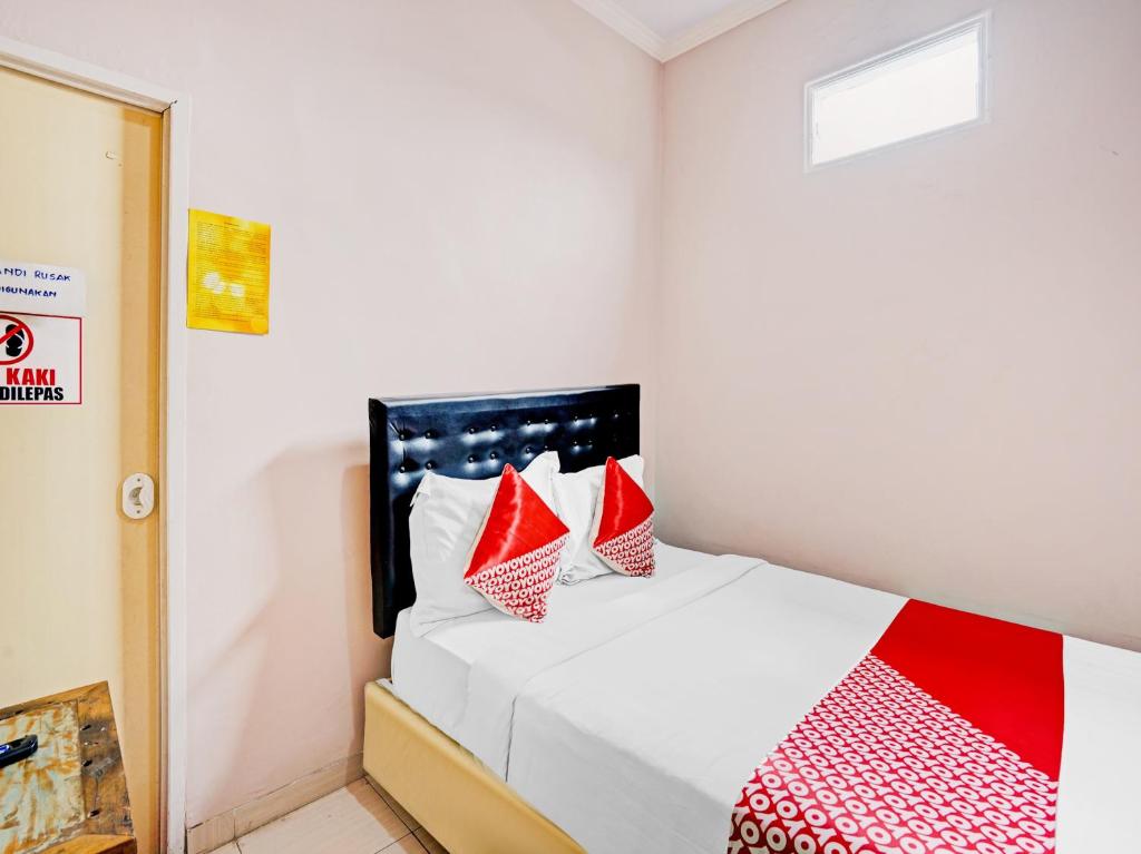 1 dormitorio con 1 cama con almohadas rojas y blancas en OYO 90234 Dhoho Family Guest House, en Kediri