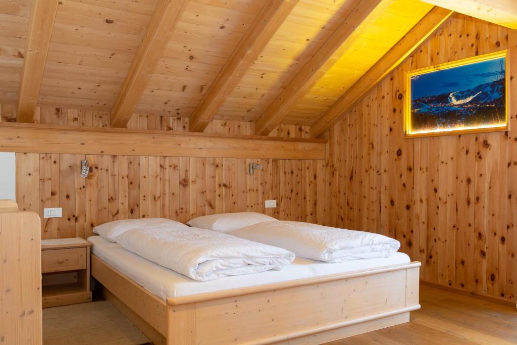 ein Schlafzimmer mit einem Bett in einem Holzzimmer in der Unterkunft B&B Ciasa Brüscia in St. Vigil