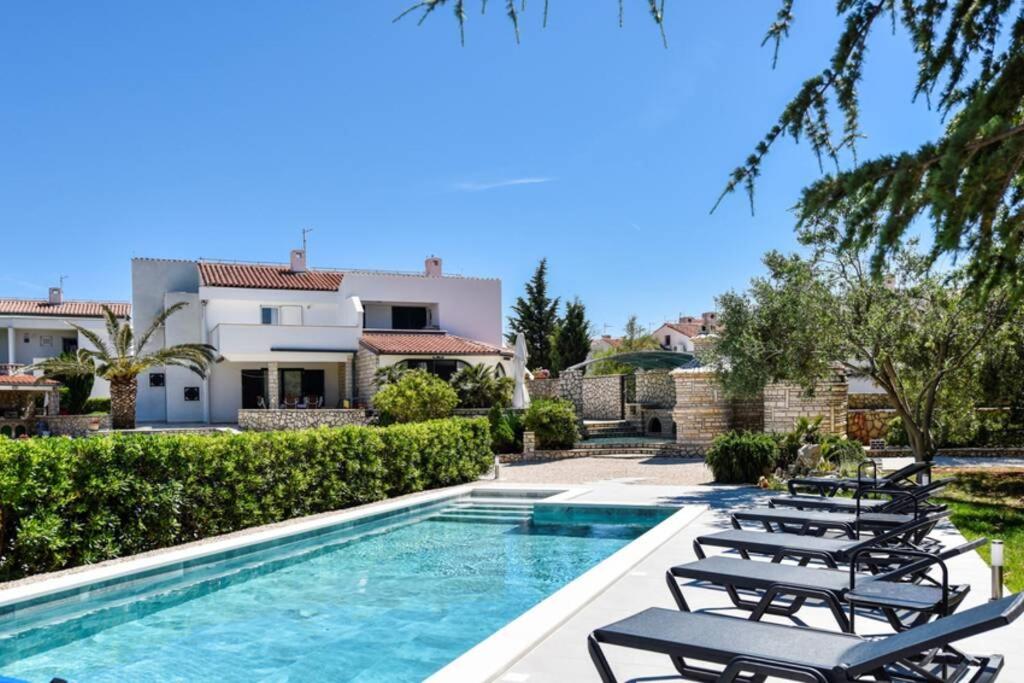 une villa avec une piscine et des chaises longues dans l'établissement Apartment in Casa Porta Luna, Gajac, Novalja, à Novalja