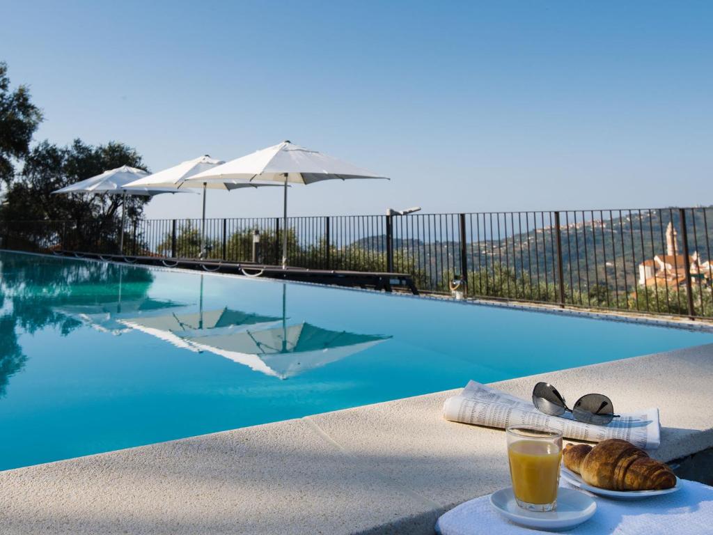 a glass of orange juice and bread next to a swimming pool at Arco del Mare - swimming pool with nice sea view in Civezza