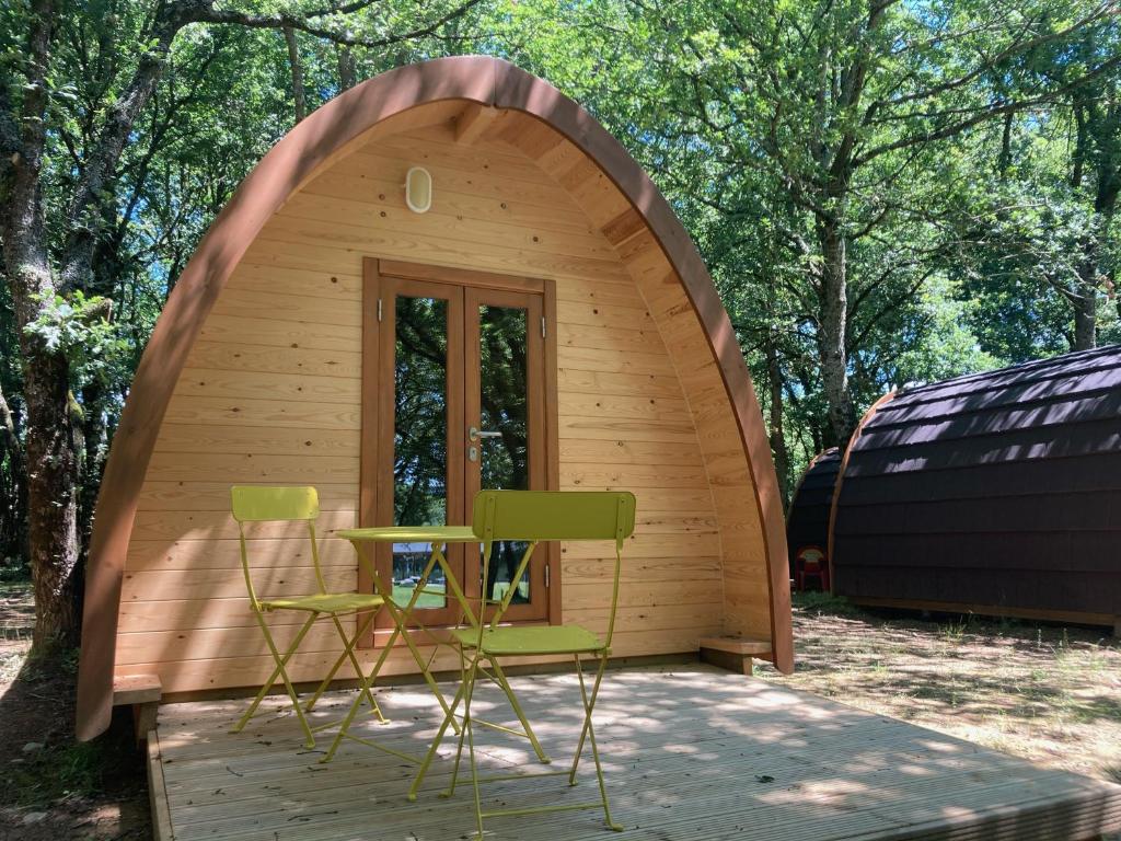 Cabaña de madera pequeña con 2 sillas y mesa en Camping Vila de Sarria, en Sarria