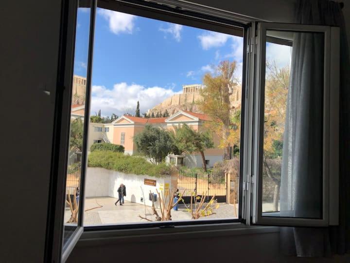 una ventana con vistas a una persona que camina por una acera en Acropolis Museum Apartment en Atenas