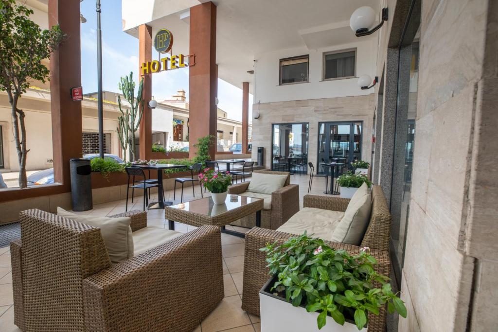 un patio con mesas y sillas de mimbre en un restaurante en Hotel De Plam, en Olbia