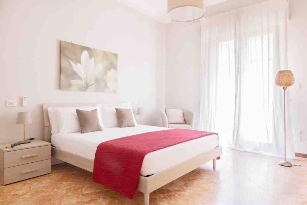 a white bedroom with a large bed with a red blanket at Cota Holidays House in Piano di Sorrento