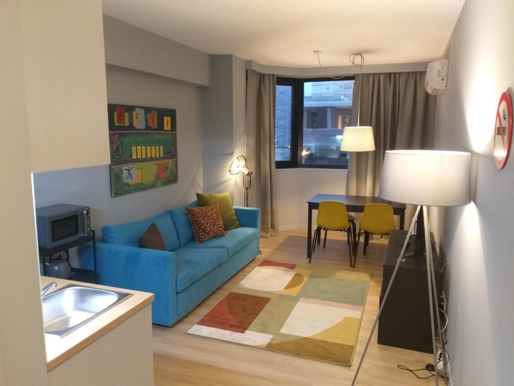 Boavista Cosy Apartments في بورتو: غرفة معيشة مع أريكة زرقاء وطاولة
