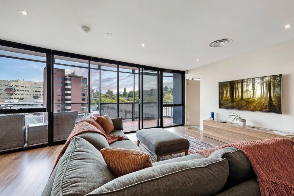 a living room with a couch and large windows at Sub Penthouse Luxe suit, CBD, secure parking, in Hobart